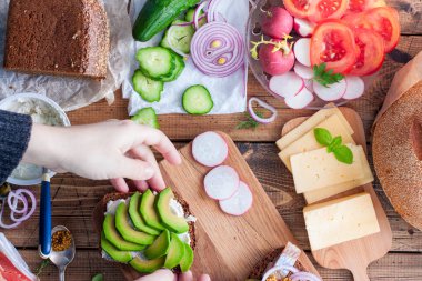 Çavdar ekmeği, üstten görünüm, mutfak konsepti, yatay açık sandviçle toplamak eller