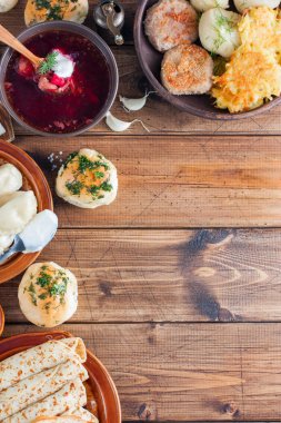 Ahşap bir masa - borsch, vareniki, pampushki sarımsak, domuz yağı, krep, patates, vvar, üstten görünüm, Ukrayna mutfağından geleneksel ev yapımı yemekler alanı Kopyala