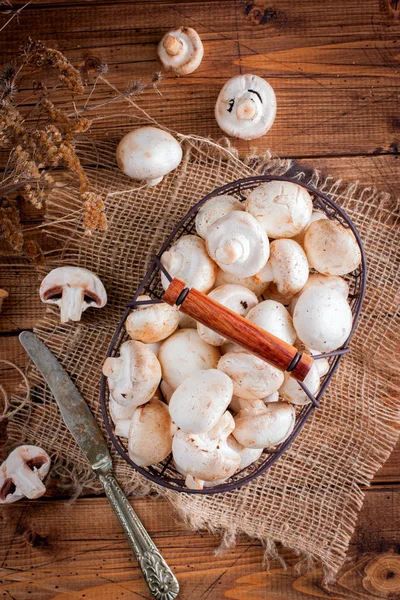 Rauwe verse champignons in een metalen mand op een houten tafel, bovenaanzicht — Stockfoto