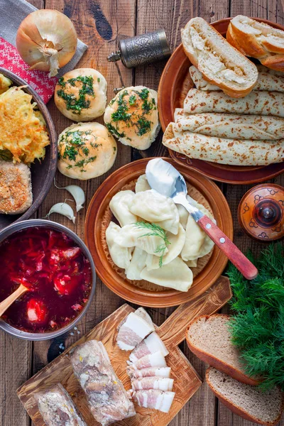 Makanan tradisional dalam masakan Ukraina - borsch, vareniki, bacon, kaldu, nalgovniki, cutlets in Kiev, dranniki, pampushki, di atas meja kayu, fokus selektif, top view — Stok Foto