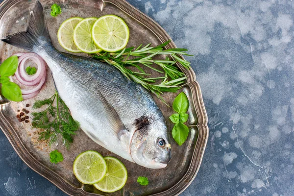 Pescado fresco crudo Dorado con hierbas frescas (albahaca, perejil, eneldo, romero), especias (sal, pimienta, hierbas secas, cebolla), lima, vista superior, horizontal, espacio para copiar — Foto de Stock