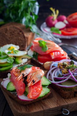 Kırmızı balık, karides, lor peyniri, seçici odak ile siyah ekmek üzerinde taze sebze ile bir açık sandviç