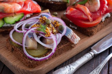 Tuzlanmış ringa balığı, salatalık, kırmızı soğan, çavdar ekmeği, seçici odak hardal ile açık sandviç