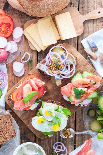 Варианты традиционных датских открытых бутербродов на ржаном хлебе на завтрак на деревянном столе, вид сверху, избирательный фокус — стоковое фото