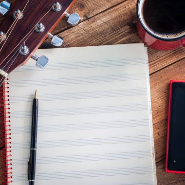 Notalar defter, gitar akbaba, kahve ve ahşap bir masa, kopya alanı, bir smartphone kare temiz