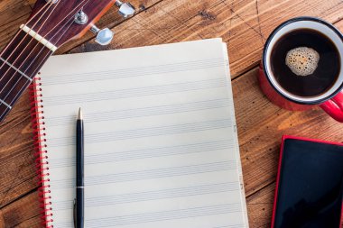 Gitar, sade kahve, smartphone ve ahşap bir masa üstü temiz Not kitap görünümü, yatay, alanı, müzik kavramı kopya