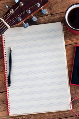 Gitar, kahve, smartphone ve temiz bir not-kitap ahşap bir masa, üstten görünüm alanı Kopyala