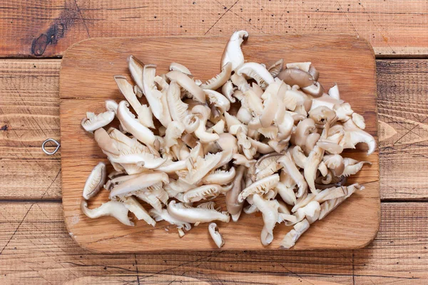 Step by step preparation of fried oyster mushrooms with onions, step 3 - slicing raw oyster mushrooms, top view, selective focus