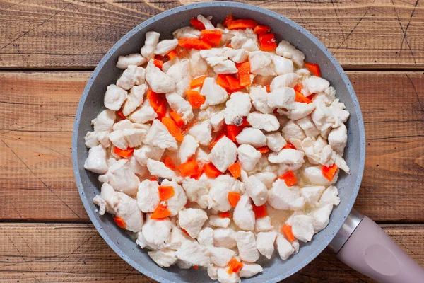 Step-by-step preparation of chicken fillet with mushrooms in sour cream sauce, step 5 - adding carrots to the fried chicken fillet, selective focus