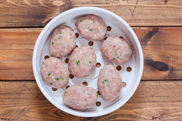 Step-by-step cooking of turkey cutlets for a couple, step 4 - forming raw cutlets and putting them on a double boiler, top view, selective focus