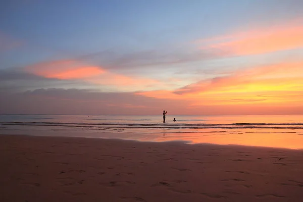 Ходячие люди на пляже на красочном закате . — стоковое фото