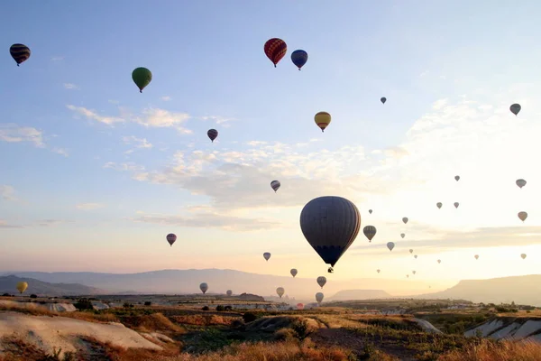 El amanecer en las montañas con una gran cantidad de globos de aire caliente en el cielo . — Foto de Stock