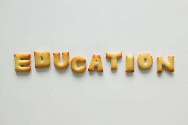 An inscription from the cookies on the white background. Text - education. — Stock Photo, Image