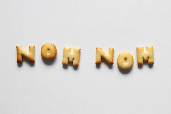 Uma inscrição dos biscoitos no fundo branco. Texto - nom nom . — Fotografia de Stock