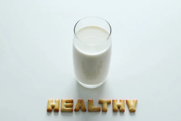 Un vaso de leche con la inscripción de las galletas en el fondo blanco . — Foto de Stock