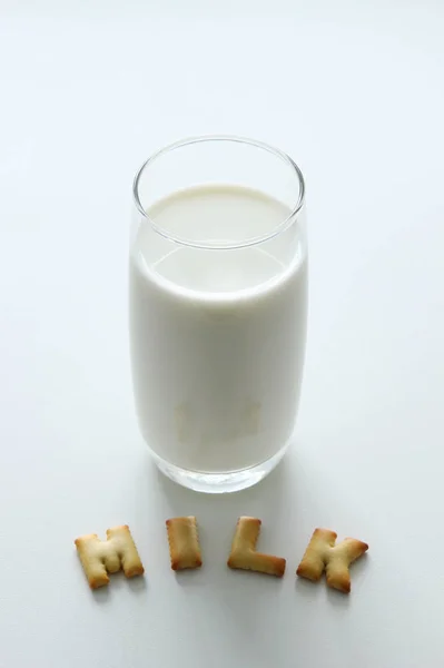 Un vaso de leche con la inscripción de las galletas en el fondo blanco . — Foto de Stock