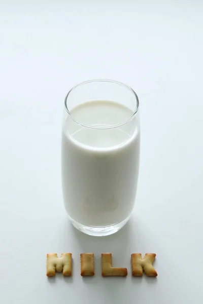 Un vaso de leche con la inscripción de las galletas en el fondo blanco . — Foto de Stock