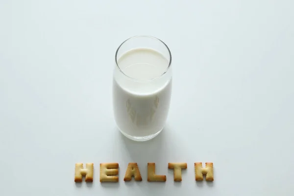 Un vaso de leche con la inscripción de las galletas en el fondo blanco . — Foto de Stock