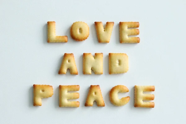 Uma inscrição dos biscoitos no fundo branco. Texto - Amor e paz . — Fotografia de Stock