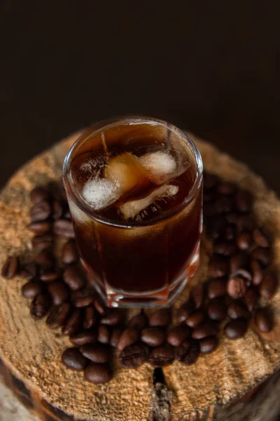 Segelas kopi es di meja kayu dengan biji kopi . — Stok Foto