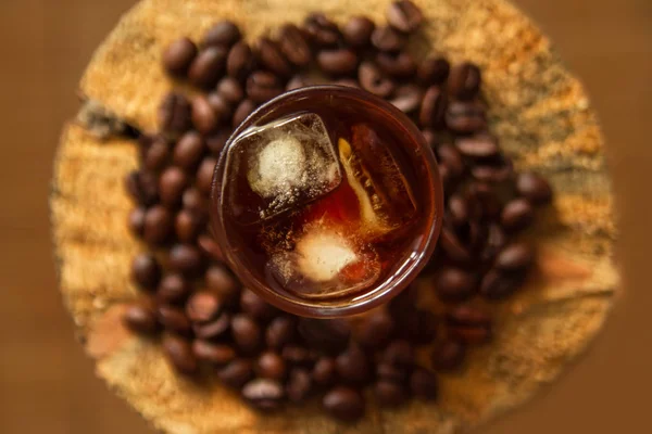 Szklanka do kawy z iceon drewniane tła z ziaren kawy. — Zdjęcie stockowe