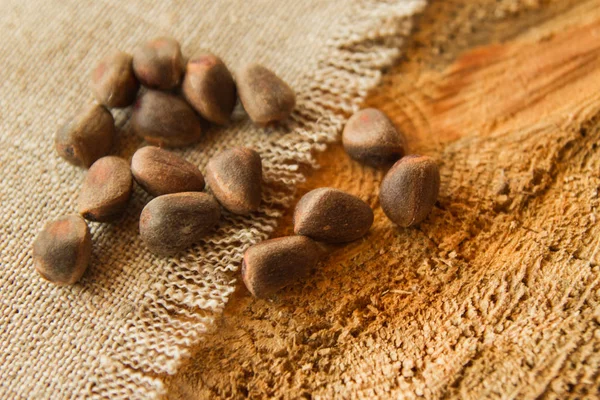 Сосновые орехи на салфетке из вретища на деревянном фоне . — стоковое фото