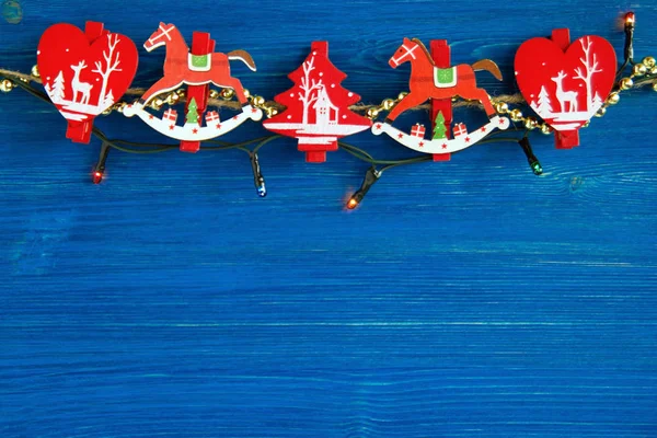 Decorações de Natal de madeira vermelha e branca e luzes de Natal no fundo de madeira azul, vista superior . — Fotografia de Stock