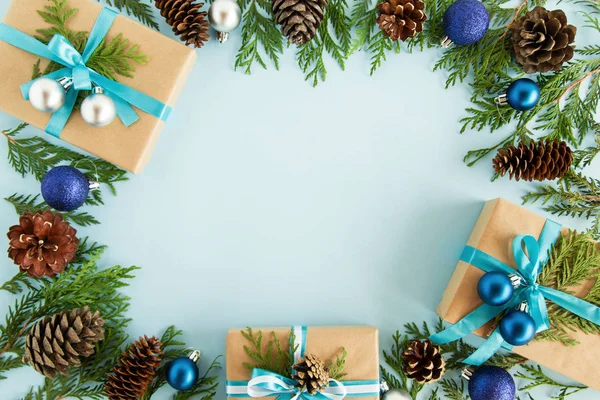 Bovenaanzicht op frame van Kerst decoraties, geschenkverpakkingen, fir takken en dennenappels op de blauwe achtergrond met kopie ruimte. — Stockfoto