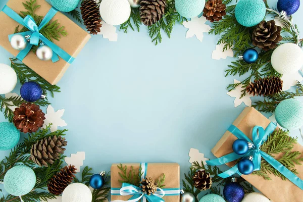Bovenaanzicht op frame van kerstversiering, geschenkverpakkingen, fir takken, dennenappels en kerstverlichting op de blauwe achtergrond met kopie ruimte. — Stockfoto