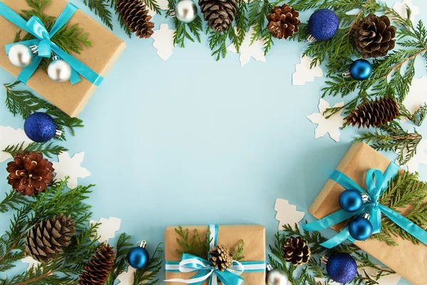 Bovenaanzicht op frame van Kerst decoraties, geschenkverpakkingen, fir takken en dennenappels op de blauwe achtergrond met kopie ruimte. — Stockfoto