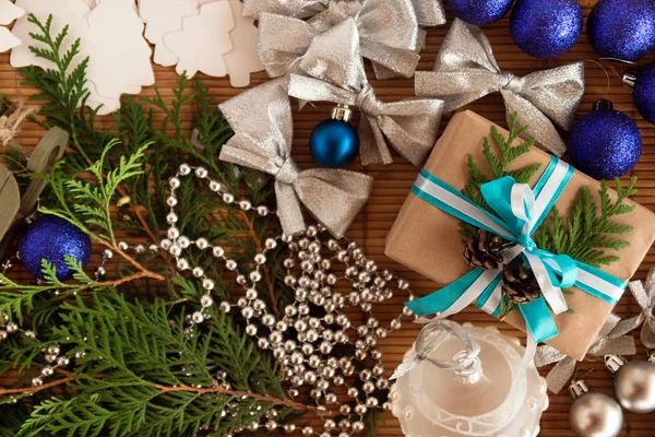 Різдвяна плоска покладена композиція ялинових гілок з подарунковою коробкою та прикрасами на коричневому дерев'яному фоні . — стокове фото