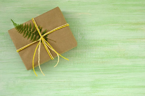 Подарункова Коробка Обгорнута Ремісничим Папером Біло Жовтою Стрічкою Листям Папороті — стокове фото