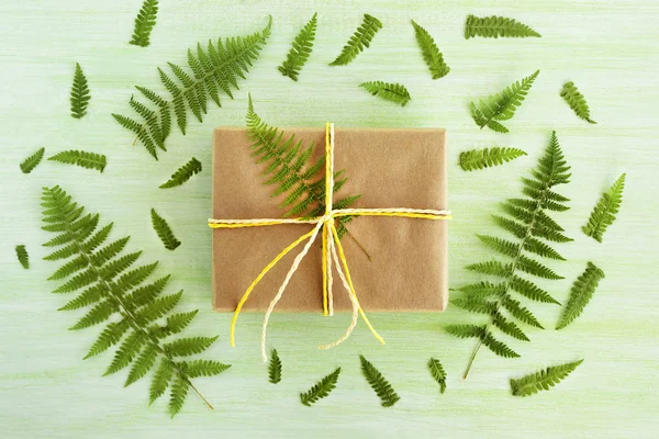 Подарункова Коробка Обгорнута Ремісничим Папером Біло Жовтою Стрічкою Зеленому Дерев — стокове фото