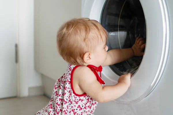 小さな女の子は洗濯機を探している — ストック写真