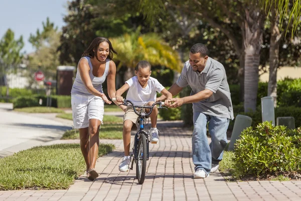 Afro-Amerikaanse familie met jongen rijden fiets & gelukkige ouders — Stockfoto