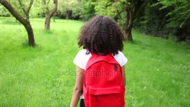 Красивая счастливая смешанная раса афро-американская девочка подросток молодая женщина походы с красным рюкзаком в зеленом яблочном саду — стоковое видео