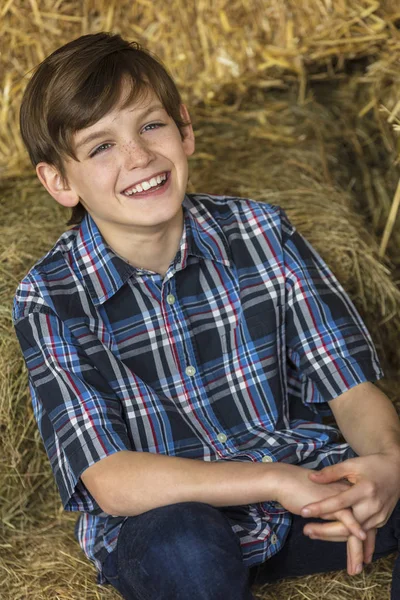 Jovem menino feliz sorrindo em fardos de feno — Fotografia de Stock