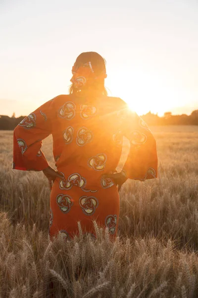 Afrikansk kvinna i traditionella kläder står i ett fält av gröda — Stockfoto