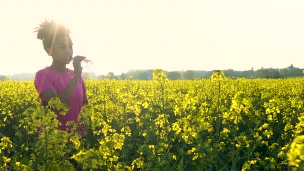 4K video clip de hermosa sana raza mixta afroamericana chica adolescente mujer joven corriendo o trotando y bebiendo una botella de agua en el campo de flores amarillas — Vídeos de Stock
