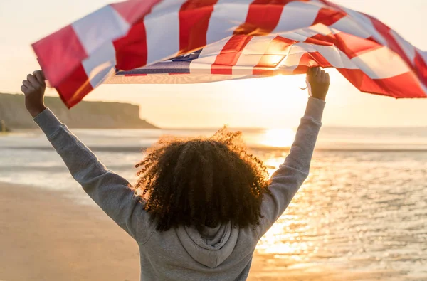 Blandad ras African American Girl tonåring med oss flagga stranden vid solnedgången — Stockfoto