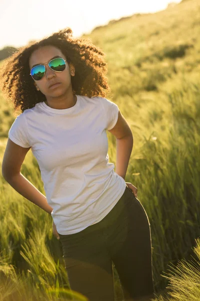 Misto raça afro-americana mulher vestindo aviador óculos de sol jeans e t-shirt no por do sol — Fotografia de Stock