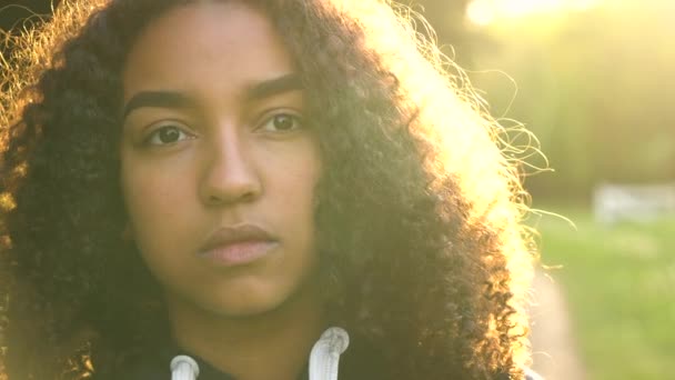 Vegyes verseny afro-amerikai lány keresi a szomorú vagy átgondolt, hátsó megvilágítású, naplementekor — Stock videók
