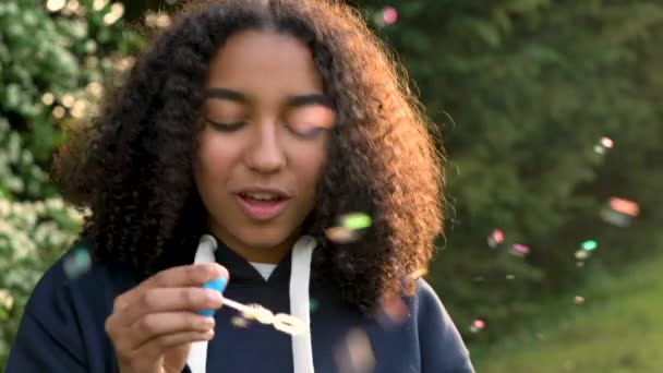 4K видео клип красивой счастливой смешанной расы афро-американская девочка подросток или молодая женщина смеется, улыбается и дует пузырьки на закате или восходе солнца — стоковое видео