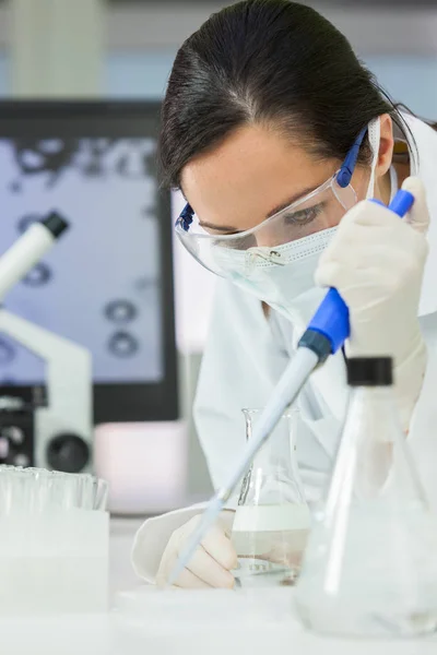 Vrouwelijke onderzoeker met Pipetteer & kolf In laboratorium — Stockfoto