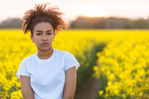 Triste razza mista afroamericana adolescente donna in fiori gialli — Foto Stock