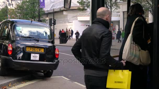 通勤タクシーと赤いロンドンバス オックスフォードの通り ロンドン イギリスにロンドンのバス オックスフォード ストリート ロンドン イギリスにタクシーと赤の二重デッカーの乗降のビデオ 2017 を取得 — ストック動画