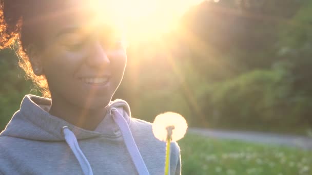 のビデオ クリップ美しい幸せな混合レース アフリカ系アメリカ人女の子のティーンエイ ジャーや若い女性の笑い 夕日や日の出 タンポポを吹く — ストック動画