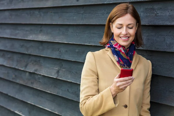 Mellomstor kvinne som bruker mobiltelefon – stockfoto