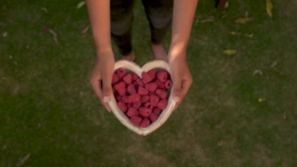 Молодая Женщина Поднимает Деревянную Чашу Форме Сердца Свежей Красной Малины — стоковое видео