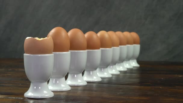 木製のテーブルの上に白い卵カップの卵の行の前にゆで卵にトースト兵士を浸し人 — ストック動画